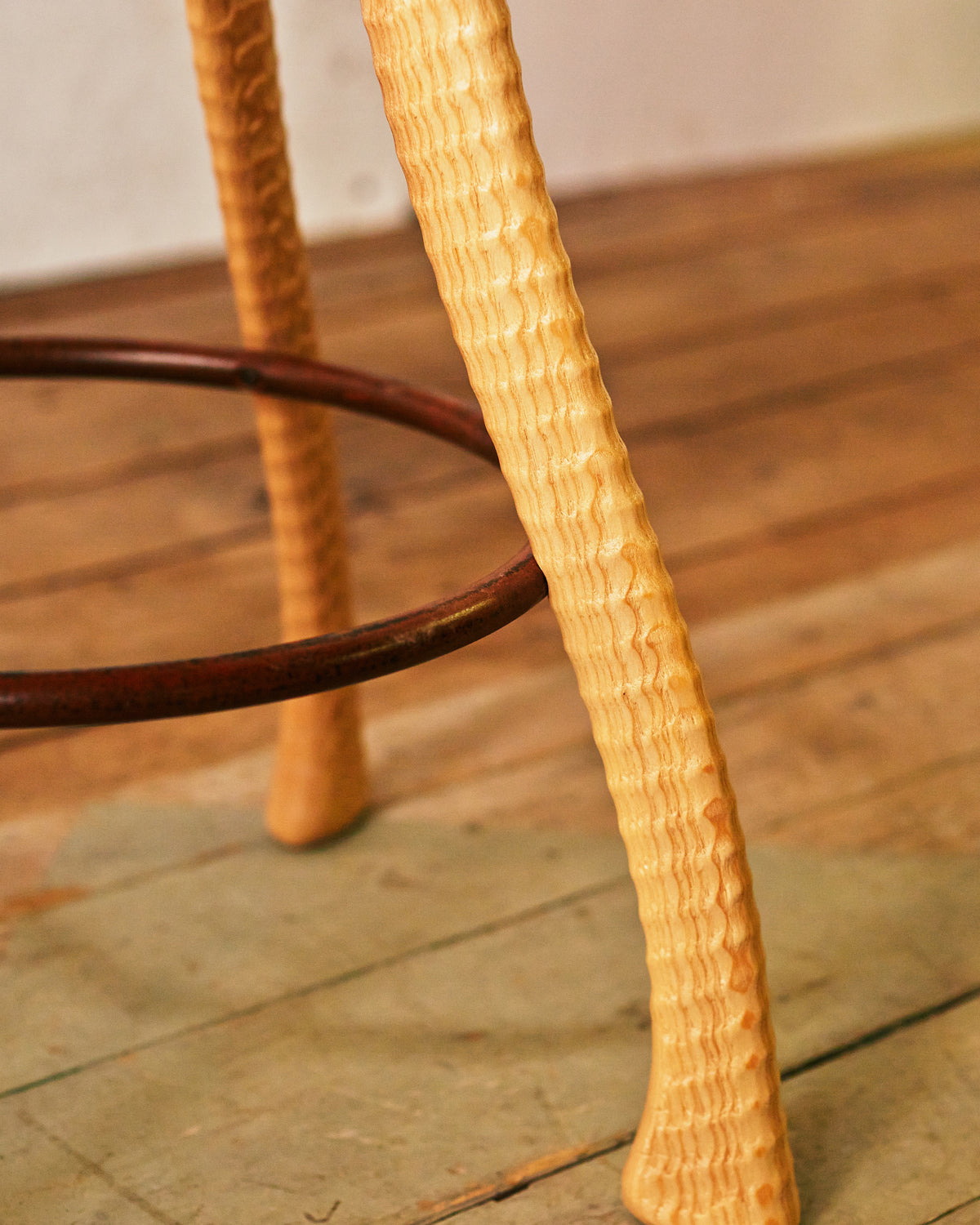 Close-up of lathe-turned ash ax handle stool leg with hand-bent iron footrest ring, Bradford Woodworking