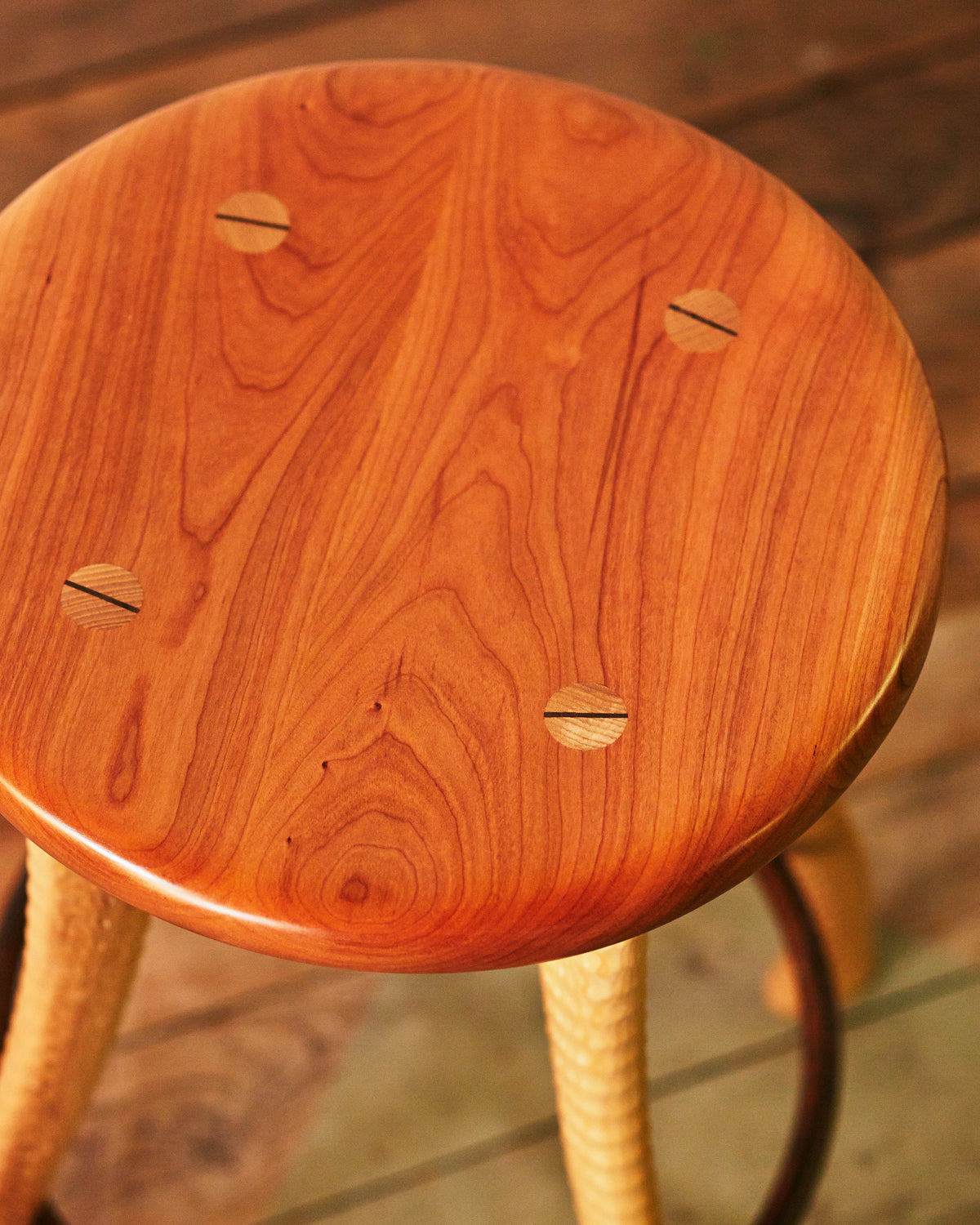 Top view of solid cherry stool seat with wedge-tenon joinery detail, Bradford Woodworking ax handle stool