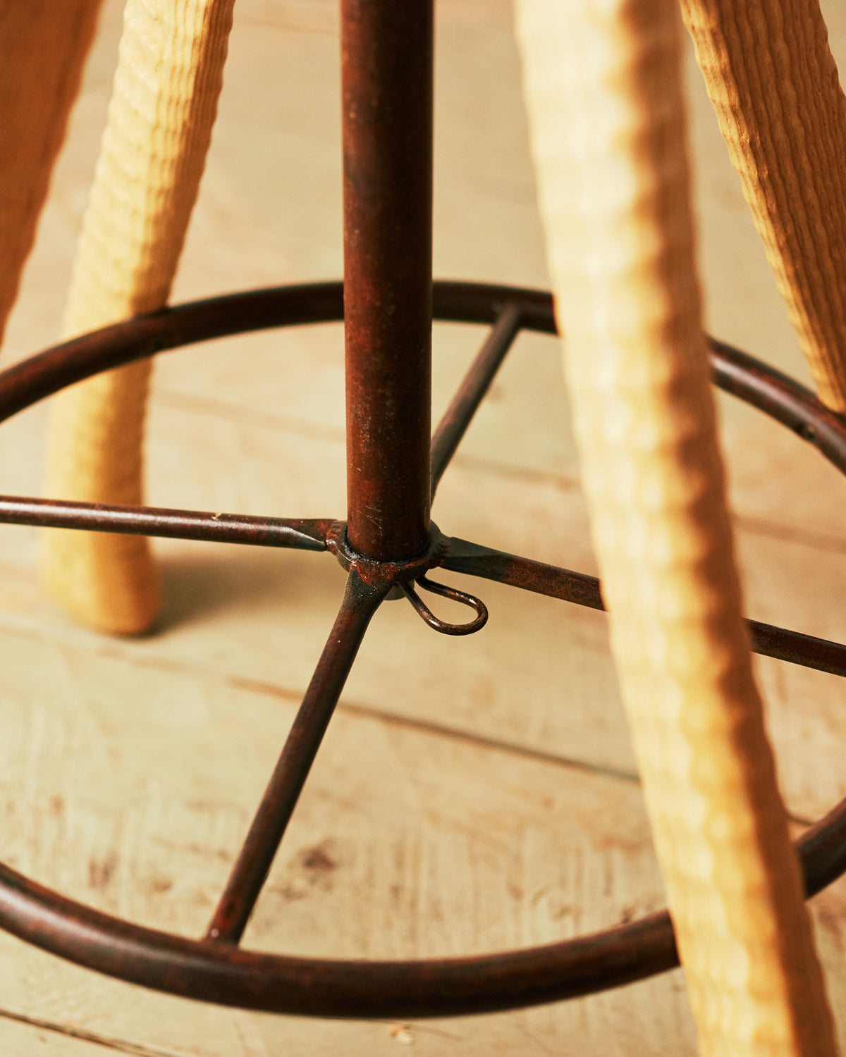Detail of hand-bent iron footrest ring and central swivel post on Bradford Woodworking tractor seat stool