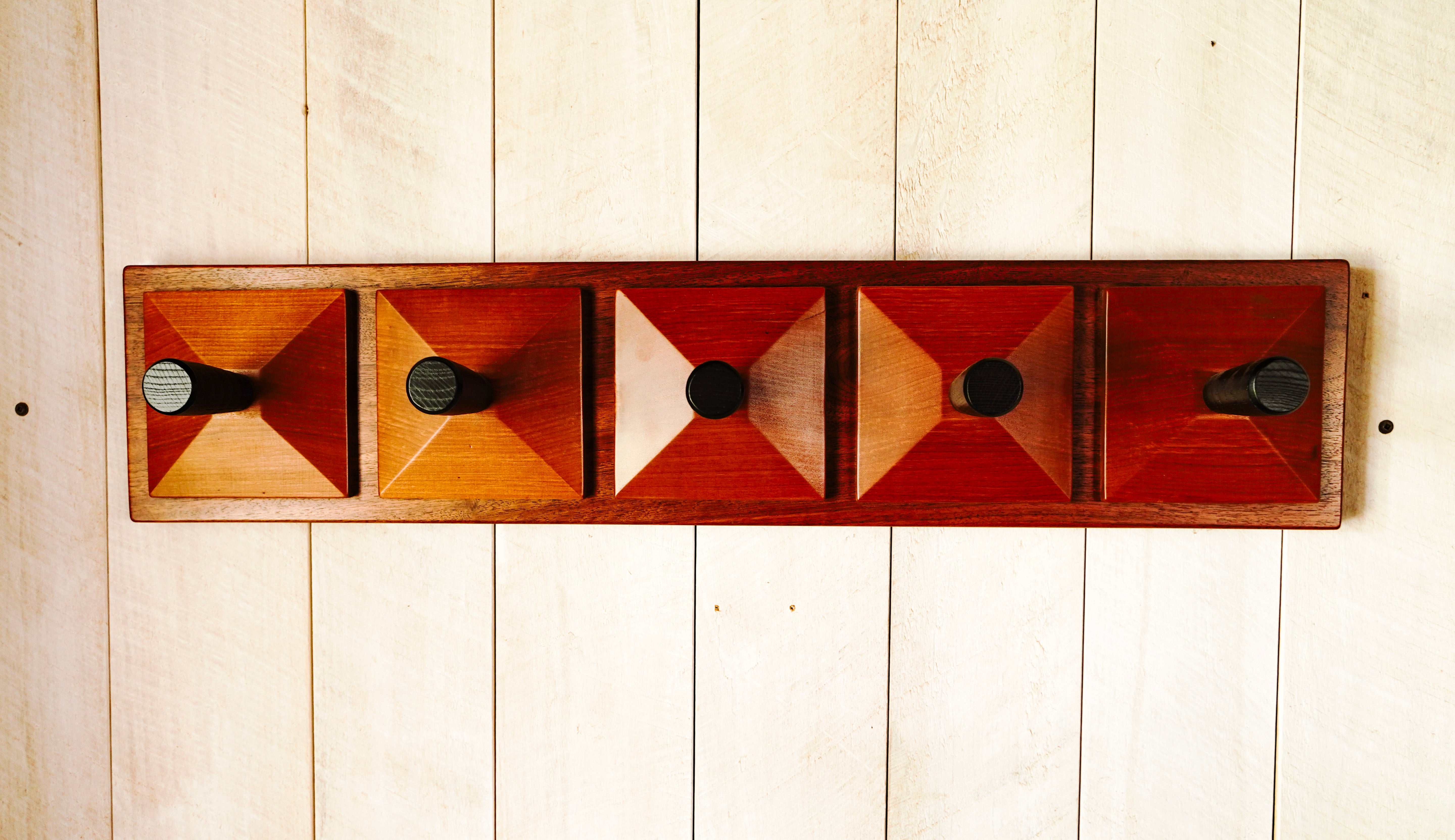 Handmade redwood pyramid coat rack with five black maple hooks mounted on a walnut base, wall-hung