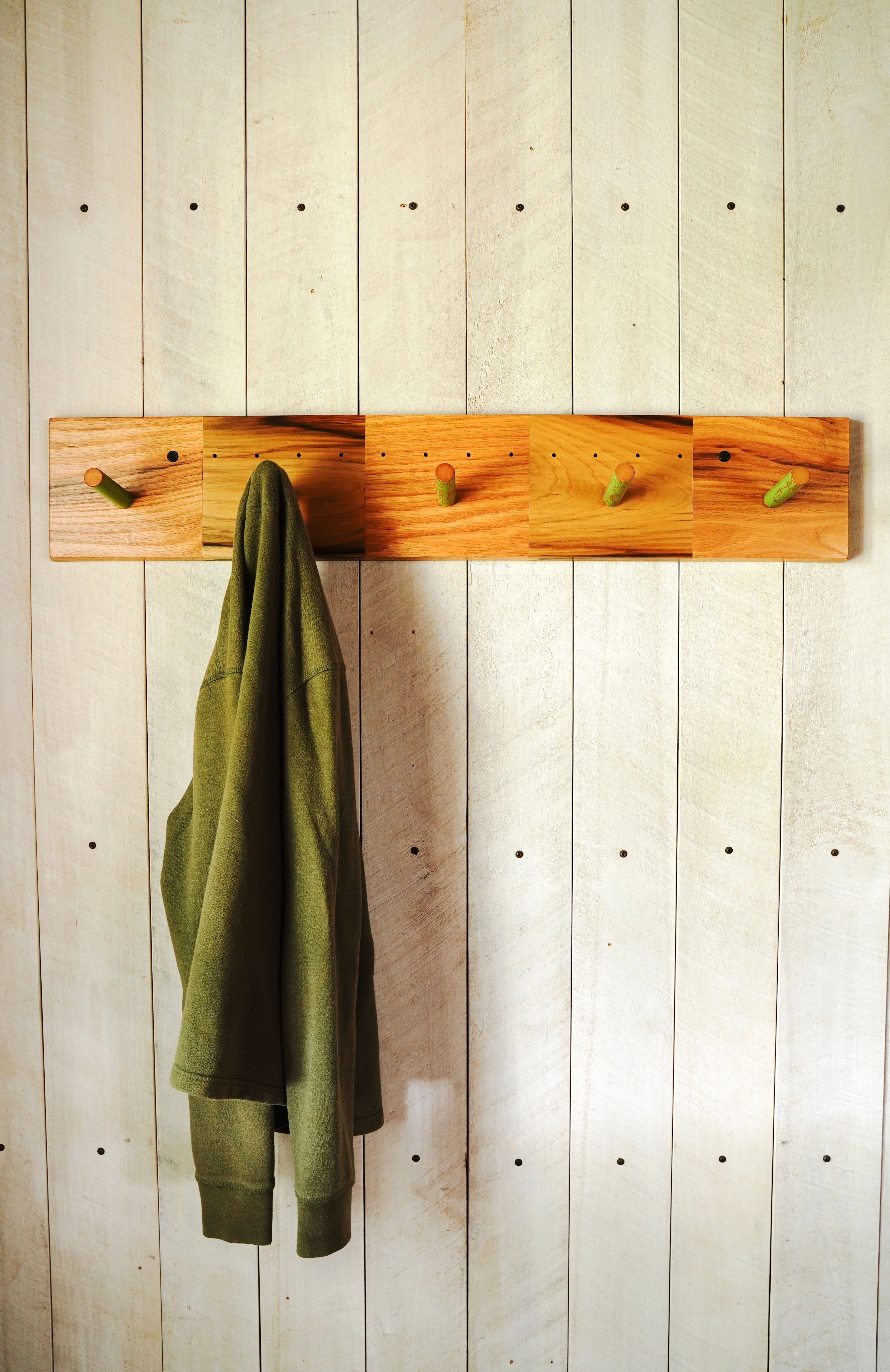Oak and ash coat rack with reclaimed broomstick hooks, styled with a sweater hanging in an entryway