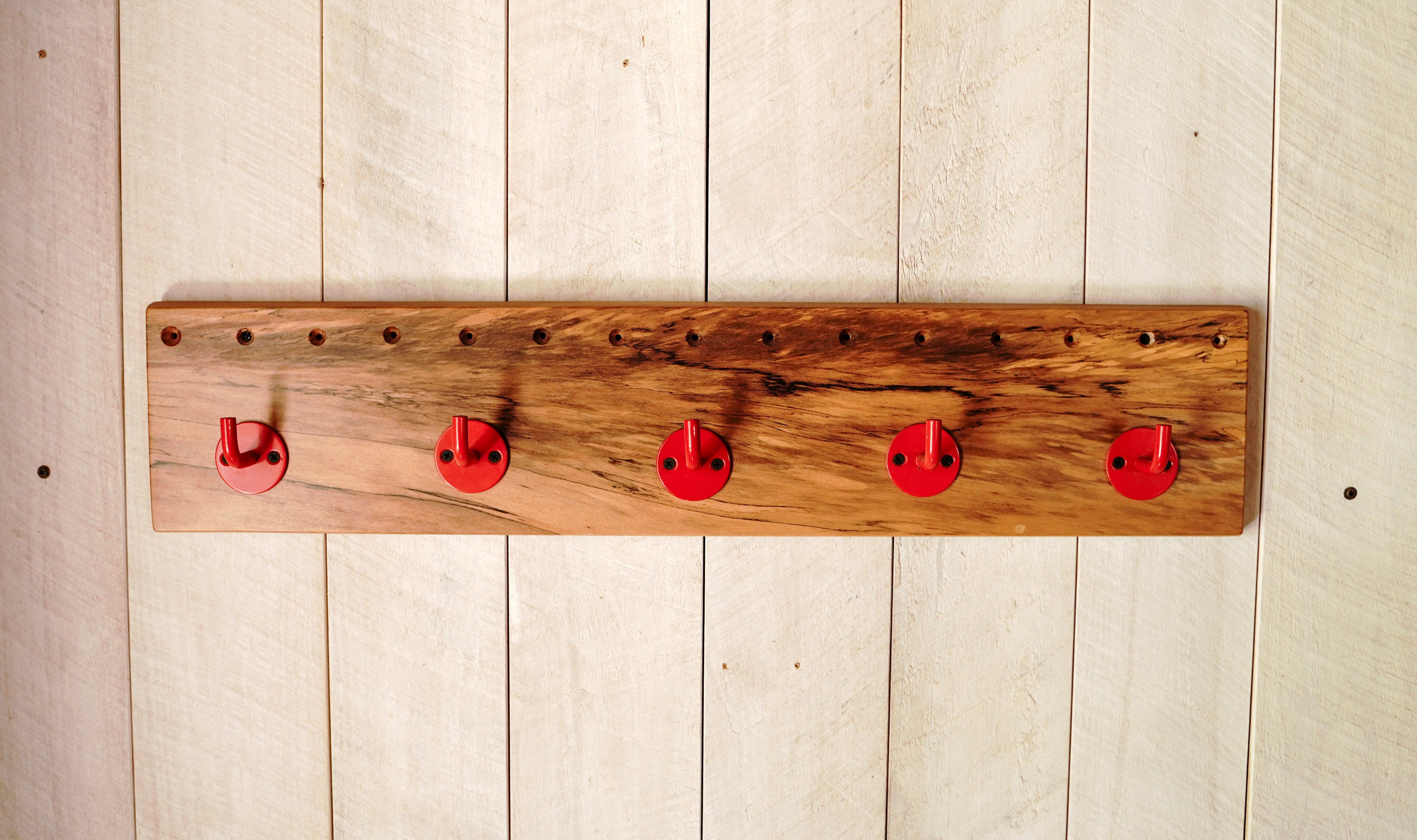 Handmade spalted maple coat rack with five red steel hooks and exposed hardware