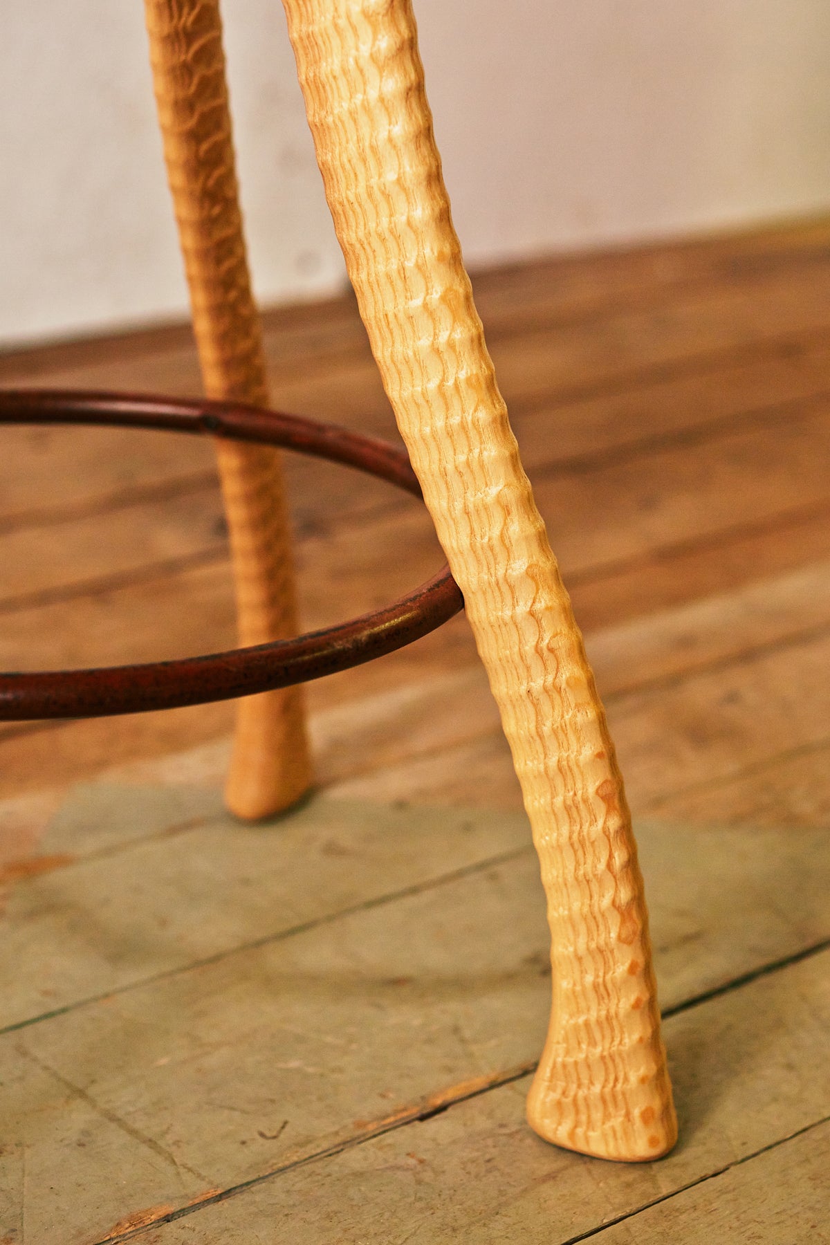 Close-up of lathe-turned ash ax handle stool leg with hand-bent iron footrest ring, Bradford Woodworking