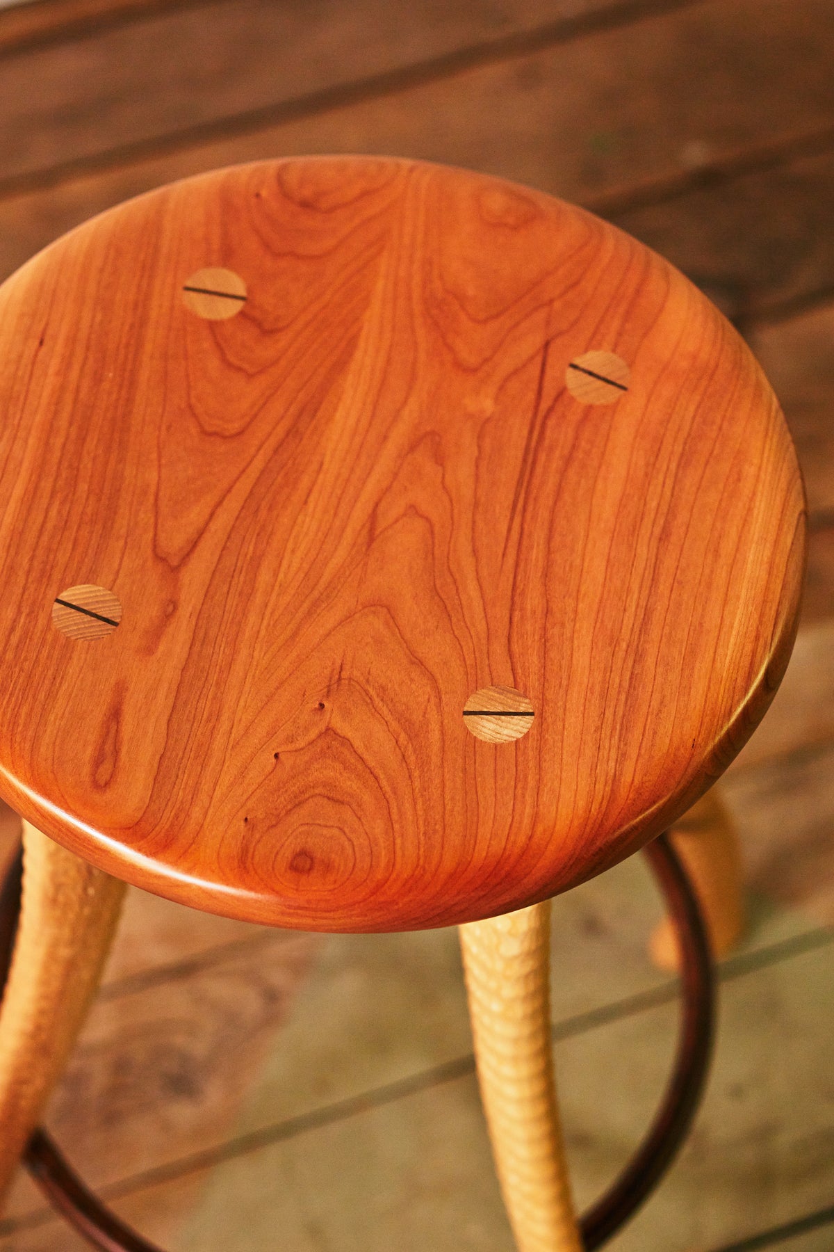 Top view of solid cherry stool seat with wedge-tenon joinery detail, Bradford Woodworking ax handle stool
